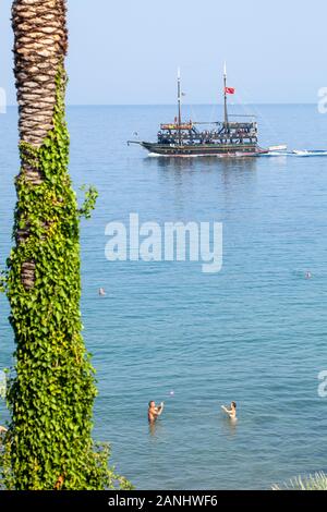 Kusadasi, Turquie - 6 septembre, 2019 : un bateau de plaisir sous la forme d'un bateau pirate navigue le long de la mer Égée, dans laquelle les gens se baigner. Un flou fragme Banque D'Images