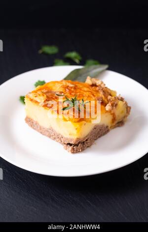 Concept alimentaire purée de pommes de terre bio faits maison de la goulasch de Bœuf sur plaque en céramique blanche sur fond noir en ardoise noire Banque D'Images