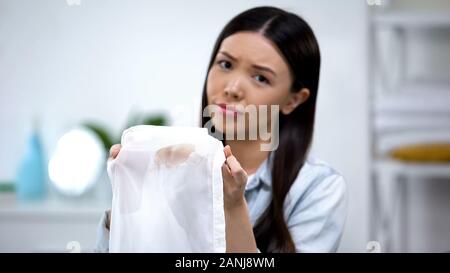 Triste ménagère asiatique montrant tache de café sur la chemise, mauvaise qualité de service de blanchisserie Banque D'Images