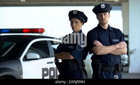 Deux braves policiers en uniforme et de service cap posant près de l'auto-patrouille, l'ordonnance Banque D'Images