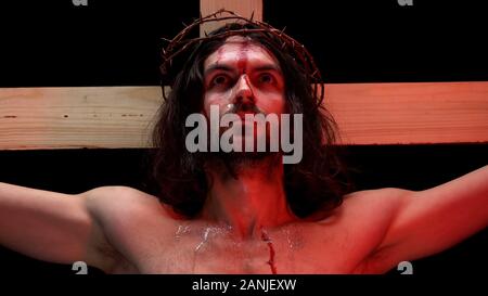 Jésus Christ souffrant l'agonie dans les feux rouges, du sang et des larmes sur le corps, la crucifixion Banque D'Images
