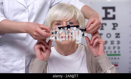 Opticien holding phoropter, préparation pour l'examen de vision vieille femme, santé