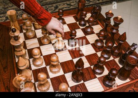 Conseil d'échecs avec de gros morceaux. Jeu d'échecs. La main de l'homme fait un pas par pion. Ensemble de pièces d'échecs. Banque D'Images