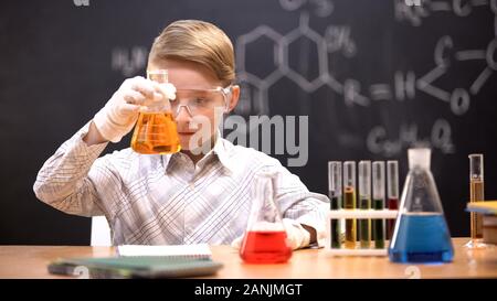 Peu de réaction d'observation chimiste liquide orange en fiole, leçon de chimie Banque D'Images