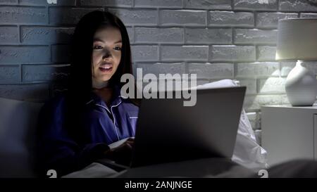 Happy woman working on laptop en pyjama à la maison, d'inspiration et de motivation Banque D'Images