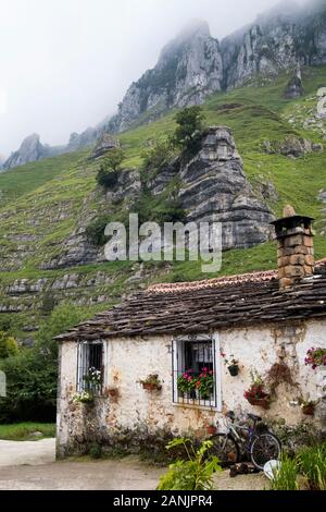 Maison traditionnelle en pierre au pied des affleurements de calcaire dans la vallée de Valle del Miera (San Roque de Riomiera, Valles Pasiegos, Cantabrie, Espagne) Banque D'Images