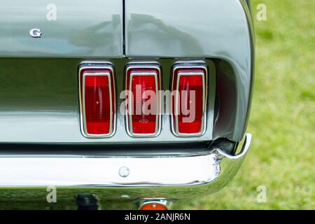 Gros plan des feux arrière de voiture d'époque sur un véhicule Ford Mustang vert classique garé sur une surface herbeuse Banque D'Images