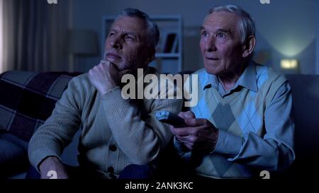 Les hommes âgés assis sur le canapé à la maison carte de commutation, soirée de détente Banque D'Images