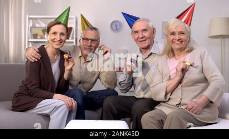 Groupe de personnes âgées de sourire en chapeaux de fête à la tenue de l'appareil photo d'avertisseur Banque D'Images