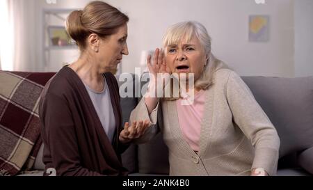 Vieille femme sourde haute écoute ami, audition, soins de santé vieillesse Banque D'Images