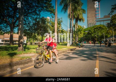 Bangkok/Thaïlande-06December2019: Parc Lumphini, vue du matin avec deux jeunes filles à vélo jaune sur la route et tour bâtiment en arrière-plan Banque D'Images