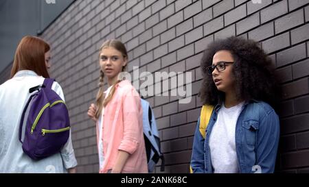 Méchant adolescents insultant black female student en lunettes, humiliation Banque D'Images