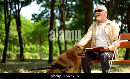 Cheerful blind man holding book et course de chiens d'assistance, de profiter de la vie Banque D'Images