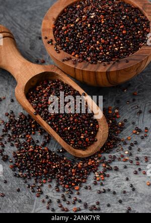 Close up of wooden scoop et bol avec les graines de quinoa noir Banque D'Images