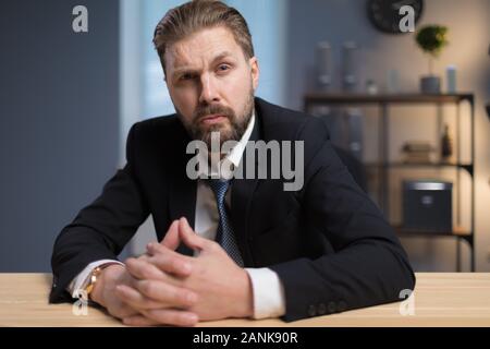 Serious Businessman sitting at Desk, son sourcil levé Banque D'Images