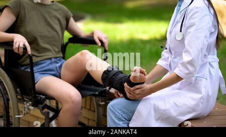 Femme médecin podiatrique l'examen d'un blessé à la jambe, la cheville brace Banque D'Images