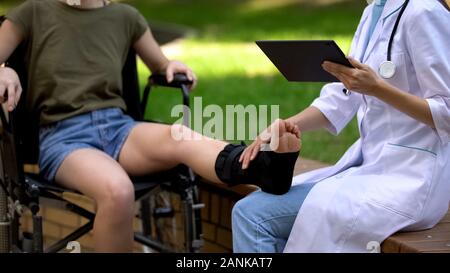 Podiatre avec tablet examining patient dans le soutien de la cheville brace, medicine Banque D'Images