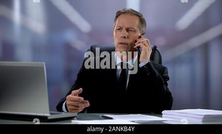 Serious businessman talking on phone avec réunion d'établissement partenaire d'affaires, Banque D'Images