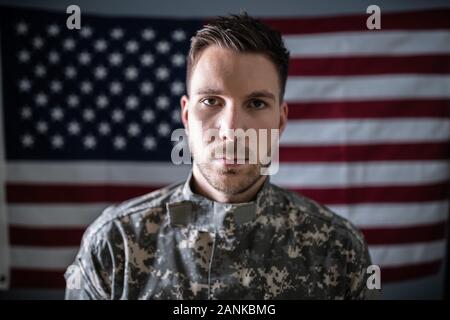 Portrait de soldat grave standing in front of Us Flag Banque D'Images
