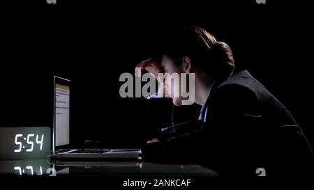 Tired woman working on laptop au quart de nuit, souffrant de migraine, surmenage Banque D'Images
