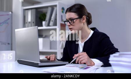 Auditeur financier responsable de la lecture des données à l'ordinateur portable et de documents commerciaux, Banque D'Images