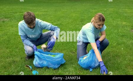 Hommes et femmes bénévoles ramasser les déchets dans la région de park smiling les uns les autres, de l'écologie Banque D'Images