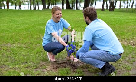 Les jeunes hommes et femmes bénévoles bush plantation parc des gaules, souriant les uns les autres Banque D'Images