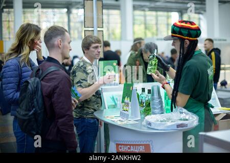 Vendeur portant chapeau Rasta jamaïcain debout au comptoir et montrant aux clients avec une bouteille de vodka (boire de l'alcool) contenant de l'extrait de cannabis Banque D'Images