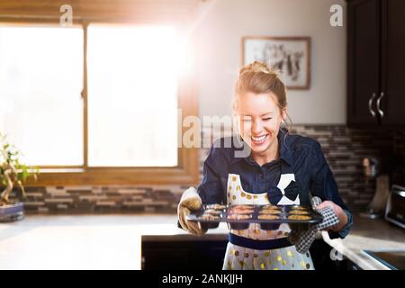 Une jeune femme affiche avec plaisir ses muffins au chocolat fraîchement cuits Banque D'Images