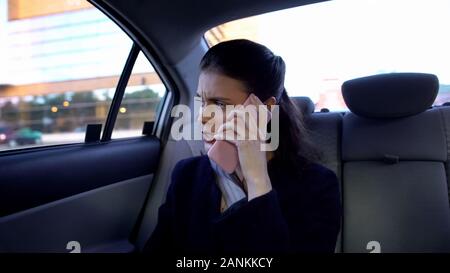 Businesswoman sitting on backseat et parlant au téléphone, travail stressant, transports Banque D'Images