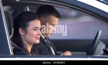 Happy woman assis près de conducteur en voiture, client satisfait avec le service de taxi Banque D'Images