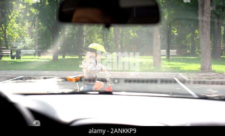 Kid riding bicycle in street, l'arrêt pilote attentif, la prévention des accidents de voiture Banque D'Images