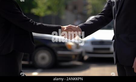 L'homme et la femme se serrer la main sur les voitures automobiles, l'arrière-plan, l'achat d'échange Banque D'Images