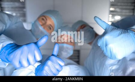 Smiling équipe de médecins showing Thumbs up, pov femme après la naissance de l'enfant, de l'hôpital Banque D'Images