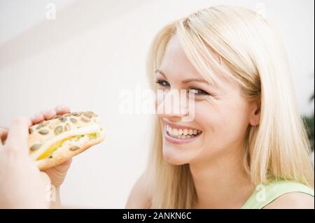 Fröhliche junge Frau hält ein Brötchen - Happy young woman holding pain Banque D'Images