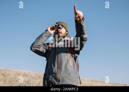 Male hiker avec main binoculaire direction de pointage Banque D'Images