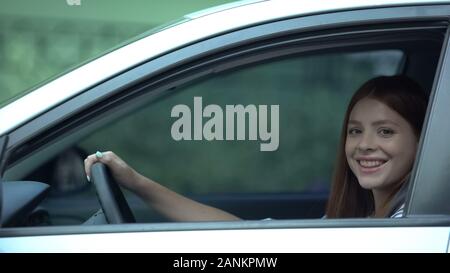 Heureux dame assise en voiture et souriant, achat attendu depuis longtemps, le crédit pour les jeunes Banque D'Images