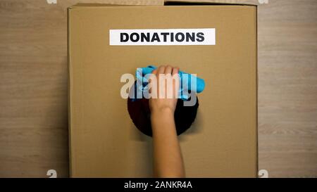 Woman putting habillement utilisé dans boîte en carton pour les dons de bienfaisance, Banque D'Images