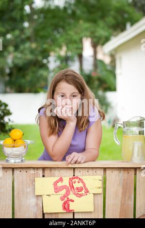 Une jeune fille ennuyée attend ses clients à son stand de limonade Banque D'Images