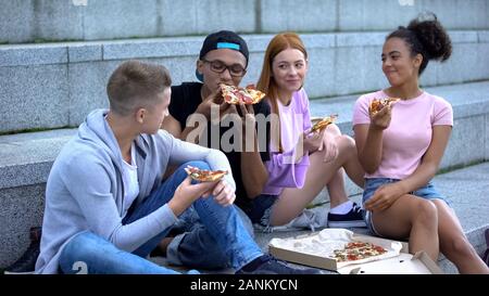 Les jeunes gens heureux de manger des pizzas à l'extérieur, les amis de détente, temps libre Banque D'Images
