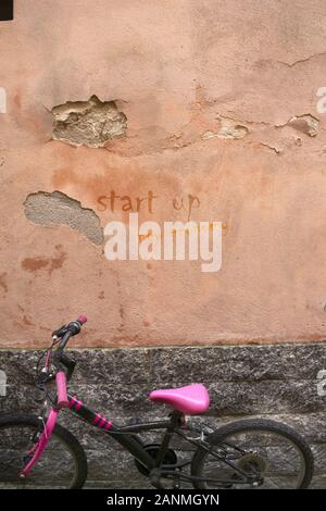 Un vieux mur avec une bicyclette et démarrage written Banque D'Images