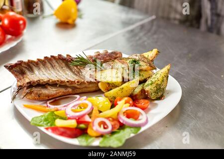 Le chef prépare dans le restaurant. Carré d'agneau grillé avec frites et légumes frais Banque D'Images