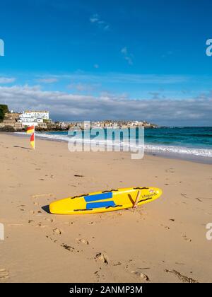 Lifeguard's palette jaune / surf / rescue board sur la plage de Porthminster, à la fin de l'été, St Ives, Cornwall, England, UK Banque D'Images