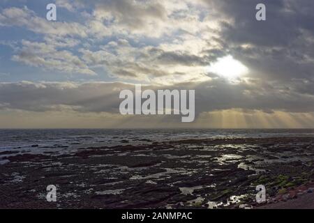 Marée basse l'exposition Rock pools à Arbroath Parc Victoria Beach sur une nature sauvage et des hivers venteux jour, avec les rayons du Soleil qui traverse les nuages Banque D'Images