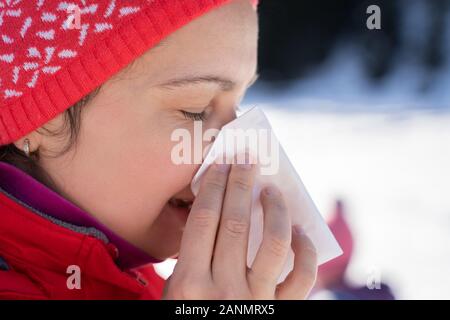 Jolie jeune femme s'être mouché le nez avec un mouchoir en hiver en plein air Banque D'Images