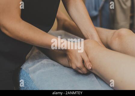Masseur massage faire le genou pour le jeune homme. Le médecin des massages la jambe pour le traitement. Banque D'Images