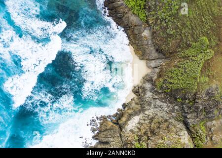 Superbe vue aérienne d'une plage cachée baignée par une mer turquoise et vert flanqué d'une falaise rocheuse. L'île de Lombok, à l'ouest de Nusa Tenggara, en Indonésie. Banque D'Images