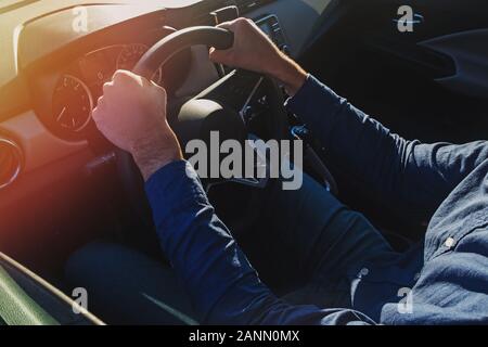 Man's hands holding le volant. La conduite sur la route, aux tons ensoleillés photo Banque D'Images