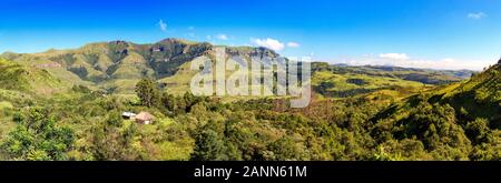 Vue panoramique sur une forêt avec une petite hutte embedded et montagnes vertes, journée ensoleillée, Drakensberg, Giants Castle Game Reserve, Afrique du Sud Banque D'Images