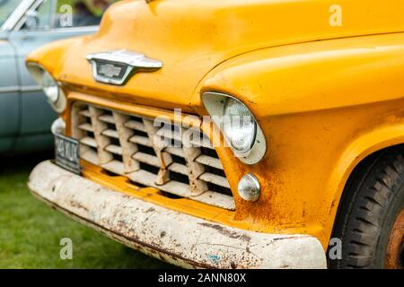 Gros plan d'un vieux camion Chevrolet jaune avec un pare-chocs rouillé stationné sur l'herbe lors d'un salon de voitures anciennes Banque D'Images